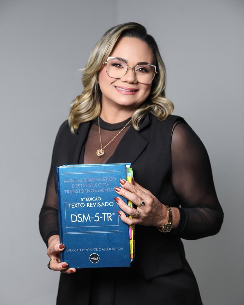Psicóloga Gionésia com manual DSM-5-TR para fundamentação diagnóstica